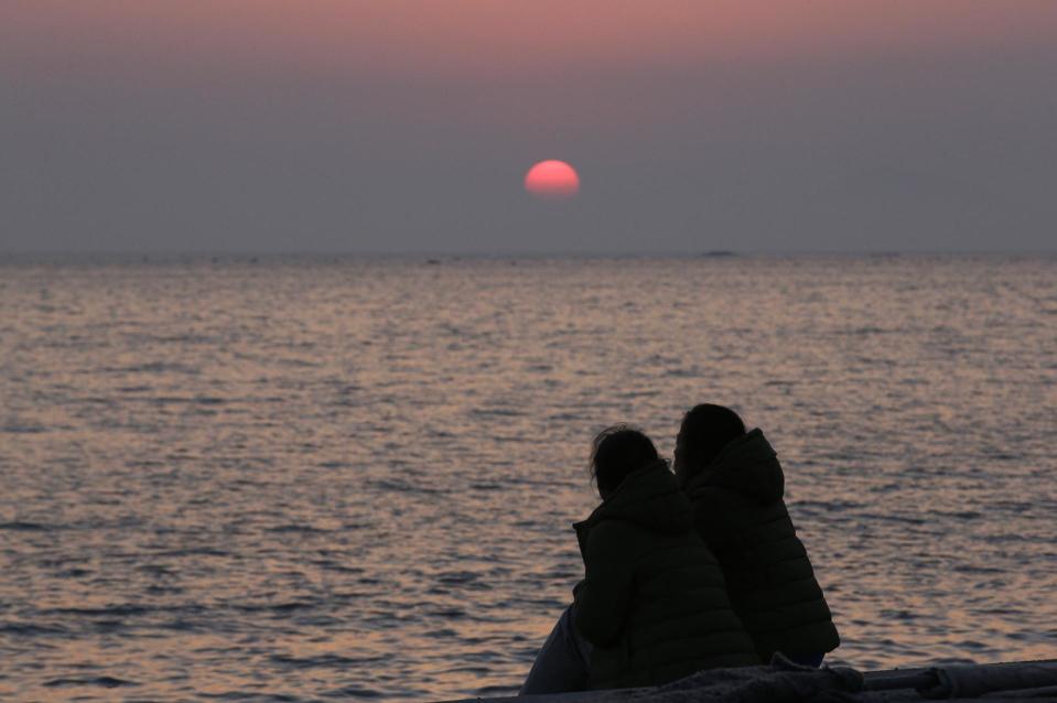 Relatives of passengers aboard the sunken ferry Sewol look towards the sea as they await news on their missing loved ones at sunset at a port in Jindo, south of Seoul, South Korea, Tuesday, April 22, 2014. One by one, coast guard officers carried the newly arrived bodies covered in white sheets from a boat to a tent on the dock of this island, the first step in identifying a sharply rising number of corpses from a South Korean ferry that sank nearly a week ago. (AP Photo/Lee Jin-man)