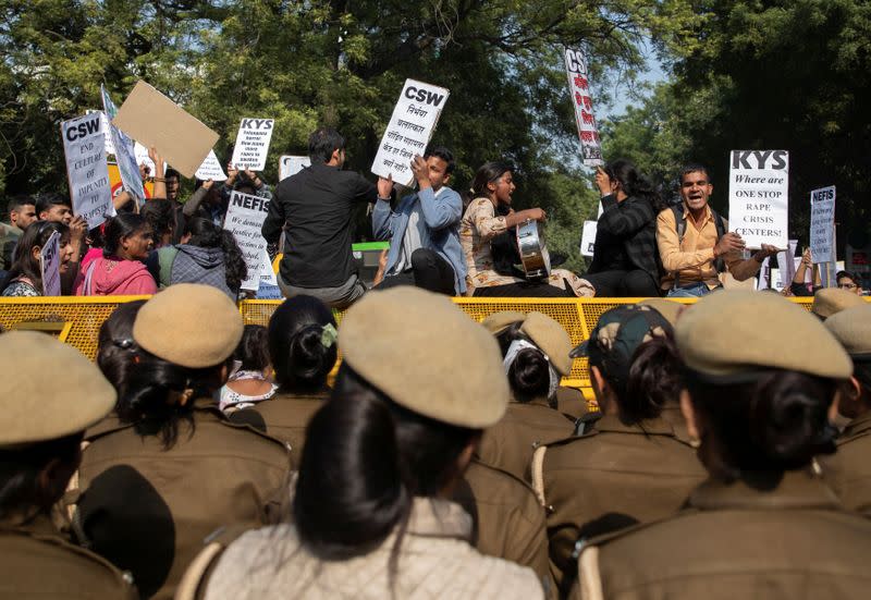 People stand on police barricades as they hold placards and shout slogans during a protest against the alleged rape and murder of a 27-year-old woman on the outskirts of Hyderabad, in New Delhi