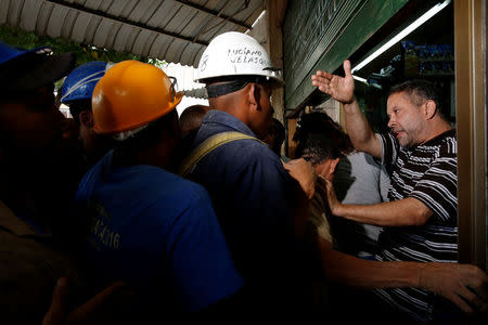 A bakery worker (R) tries to control the crowd as people queue to buy bread in Caracas July 21, 2016. REUTERS/Carlos Garcia Rawlins