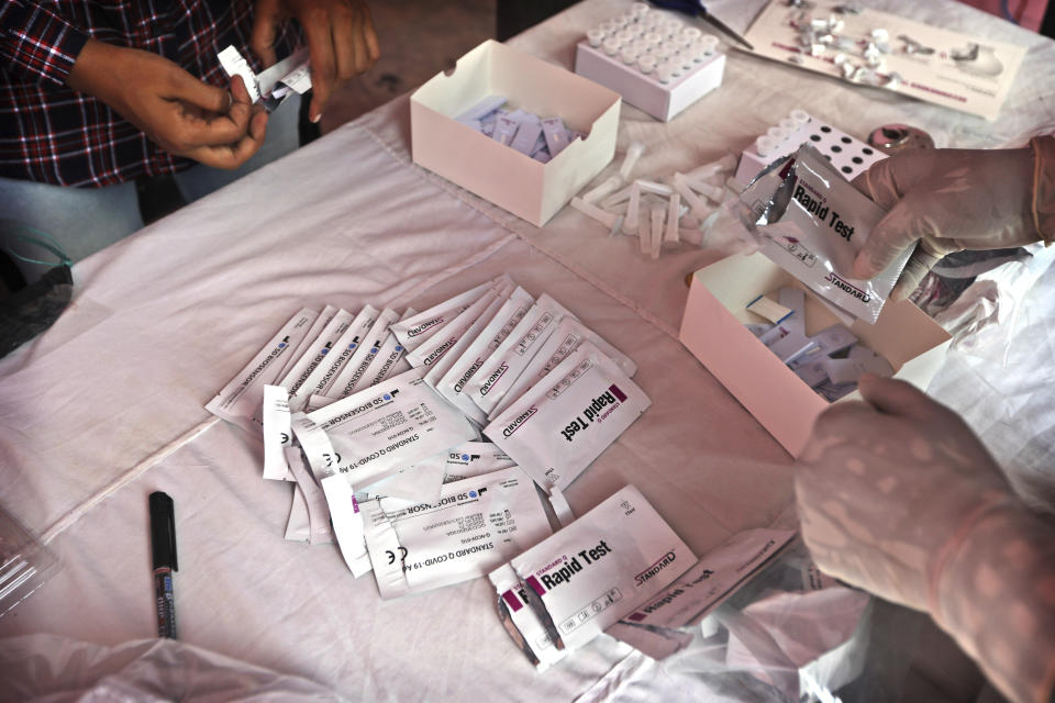 FILE - In this Aug. 7, 2020, file photo, health workers prepare for COVID- 19 antigen tests at a neighborhood, in New Delhi, India. In June, India began using the cheaper, faster but less accurate tests to scale up testing for the coronavirus — a strategy that the U.S. is now considering. (AP Photo/Manish Swarup, File)