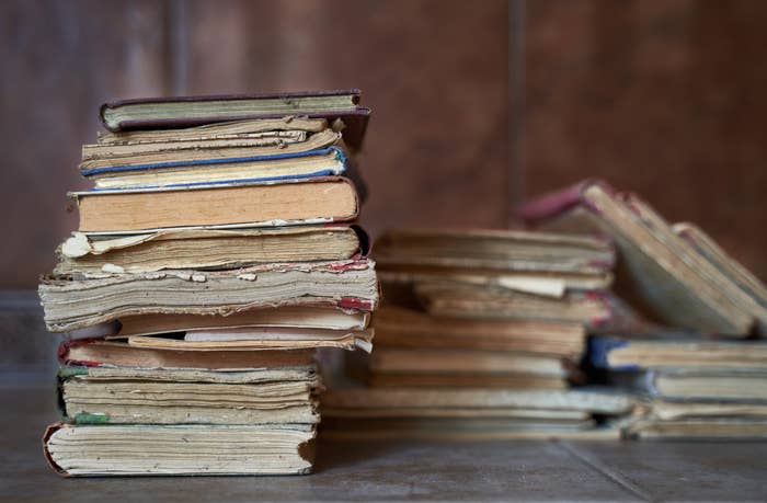 A pile of old books for donation that clearly need repair