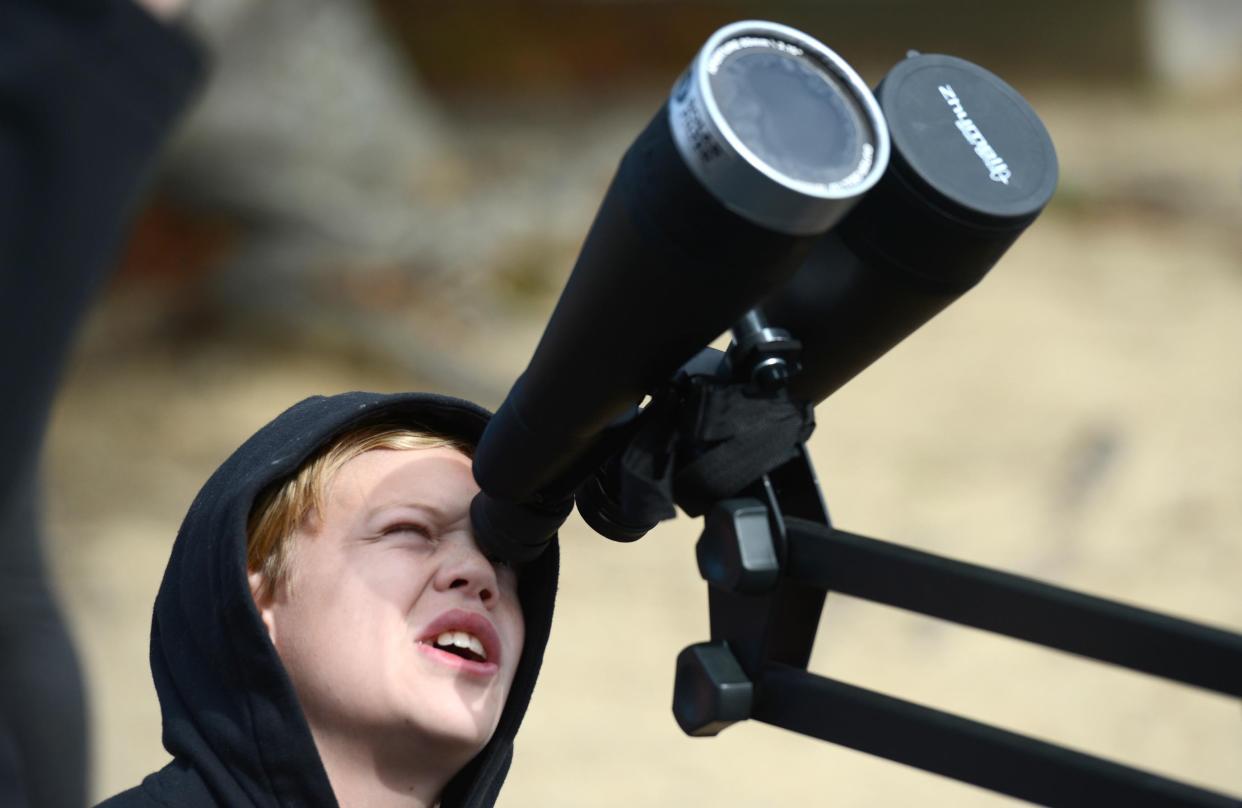 Tycon Averett looks through a pair of binoculars fitted with a solar filter to observe a mid-day annular eclipse of the sun in October 2023 at the Harwich Observatory. Early arrivers got a glimpse of last year's partial eclipse before the clouds took over the sky.