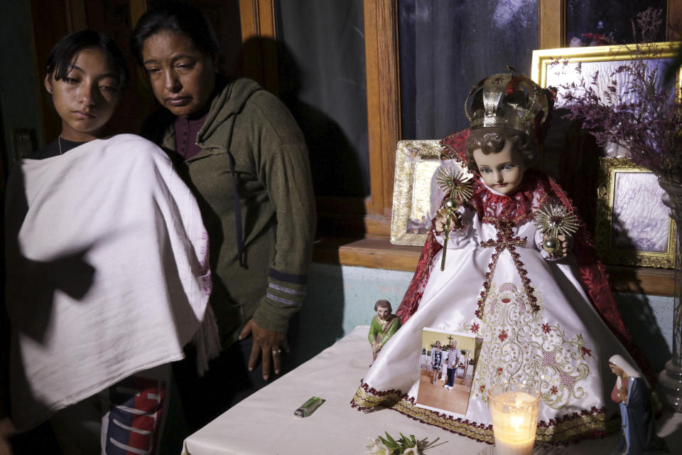 Familiares del temporero Manuel Pérez Ríos, que falleció en un accidente de bus en Florida, junto a un altar en su casa adornado con una estatua del niño Jesús, durante una vigilia en Barrio San Pedro, Oaxaca, México, el 15 de mayo de 2024. Un conductor bebido sacó de la carretera a un bus que llevaba trabajadores agrícolas a una plantación de sandías en el centro de Florida, que volcó en un campo matando a ocho personas, incluyendo Pérez Ríos, e hiriendo a docenas más, según las autoridades. (AP Foto/María Alférez)