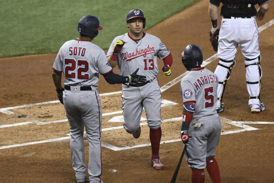 Juan Soto felicita a su compañero de los Nacionales de Washington Asdrúbal Cabrera luego de que ambos anotaron en el doblete de Kurt Suzuki en el primer inning del segundo juego de una doble cartelera ante los Marlins de Miami, el domingo 20 de septiembre de 2020, en Miami. (AP Foto/Gaston De Cardenas)