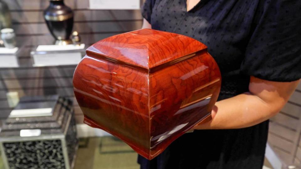 Virginia Kerr Zoller, acting manager for Kerr Brothers Funeral Home, holds one of the many types of urns offered at the funeral home for cremation services, on Sept. 13, 2023.