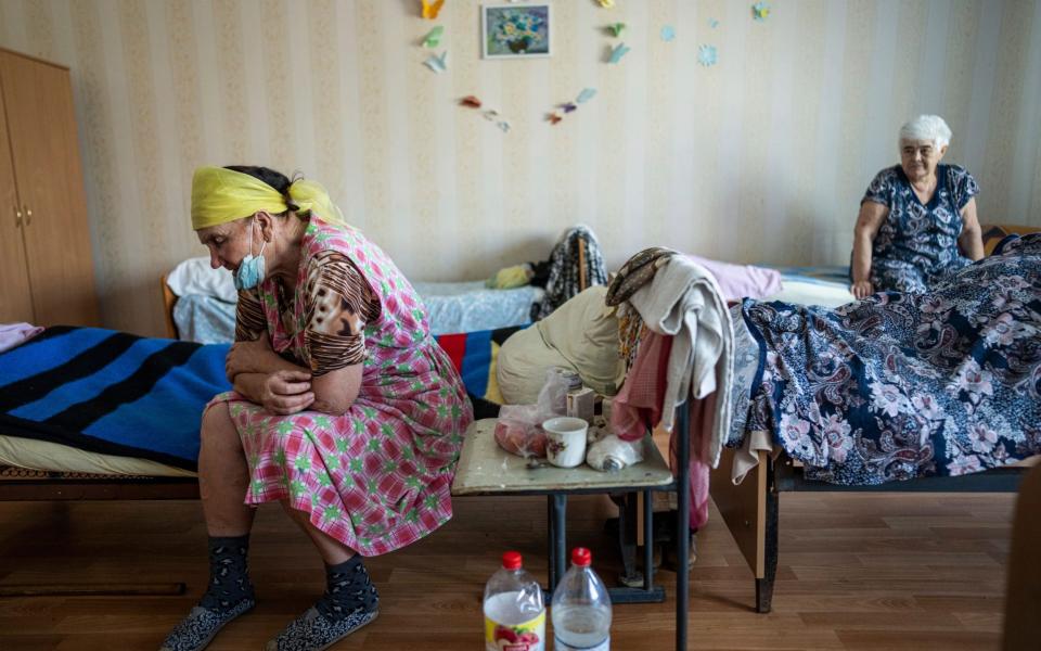 Vera Vasiukova, 71, left, sits on her bed at a center for displaced people near Mykolaiv - Evgeniy Maloletka/AP