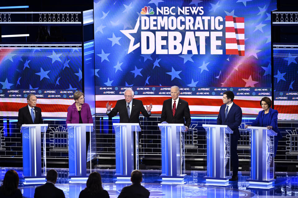 Six candidates at a Democratic debate on stage behind podiums with an NBC News backdrop