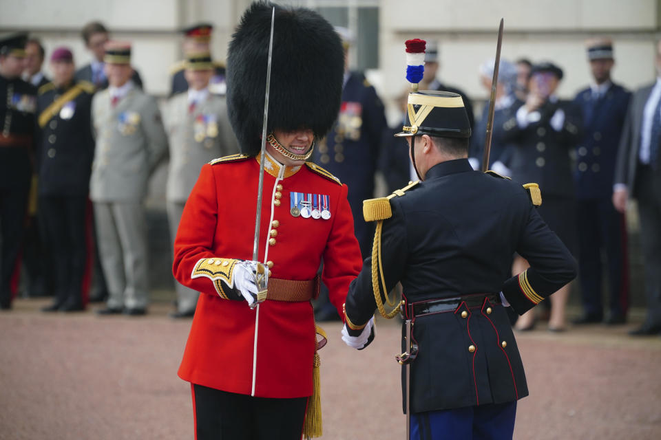 A member of the Scots Guards and a member of France's 1er Regiment de le Garde Republicaine shake hands as they partake in the Changing of the Guard ceremony at Buckingham Palace, to commemorate the 120th anniversary of the Entente Cordiale - the historic diplomatic agreement between Britain and France which laid the groundwork for their collaboration in both world wars, in London, Monday, April 8, 2024. France is the first non-Commonwealth country to take part in the Changing of the Guard. (Victoria Jones/Pool Photo via AP)