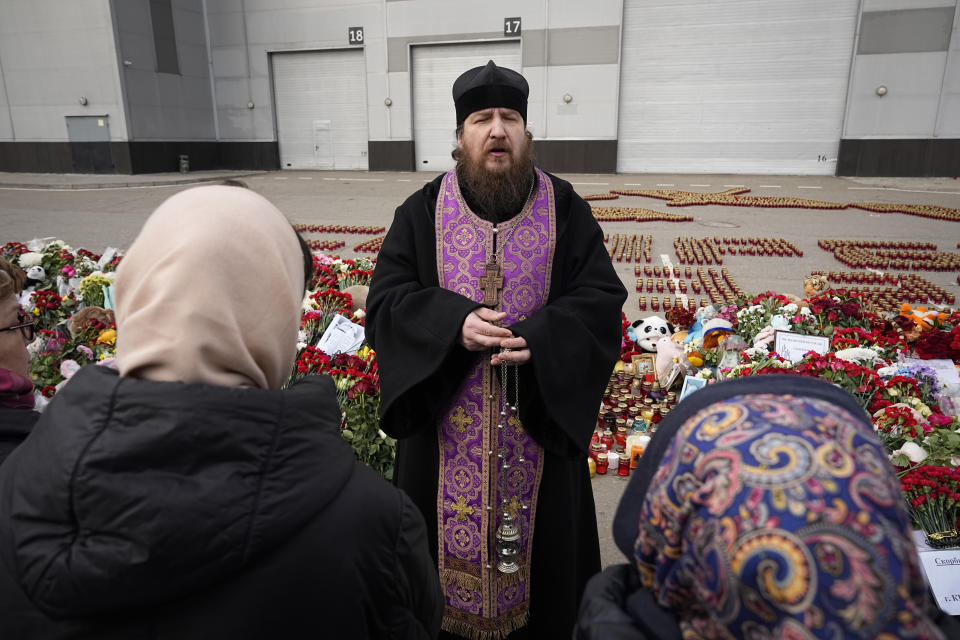 An Orthodox priest conducts a service at a makeshift memorial in front of the Crocus City Hall on the western outskirts of Moscow, Russia, Tuesday, March 26, 2024. Russian state news agency Tass says 22 victims of the concert hall attack that killed more than 130 people remain in serious condition in the hospital. (AP Photo/Alexander Zemlianichenko)