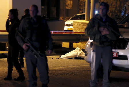 Israeli troops stand next to the covered body of a Palestinian whom they shot dead near the A-Zayyim checkpoint on the outskirts of East Jerusalem in the occupied West Bank April 25, 2015. REUTERS/Ammar Awad