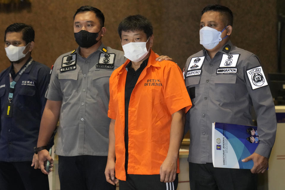 Immigration officers escort Japanese fugitive Mitsuhiro Taniguchi, center, who was arrested on Sumatra island in early June, prior to his deportation in Jakarta, Indonesia, Wednesday, June 22, 2022. Indonesia on Wednesday deported Taniguchi who was wanted by Japanese police for COVID-19 subsidy fraud. (AP Photo/Dita Alangkara)