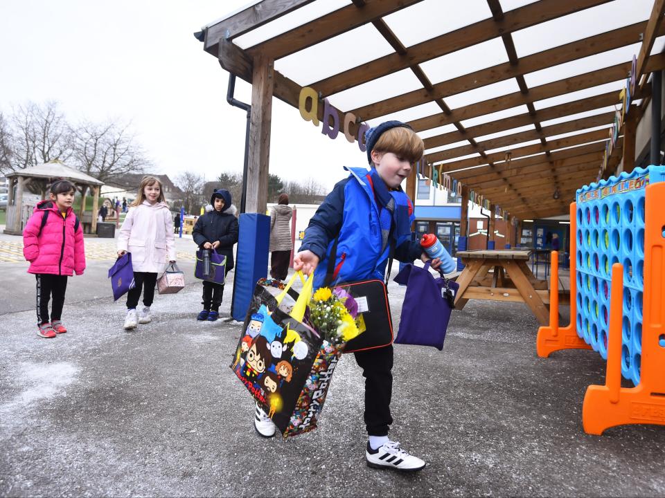 A boy arrives at St Mary’s CE Primary School with gifts for his teacher on 8 March 2021 in Stoke on Trent (Getty)