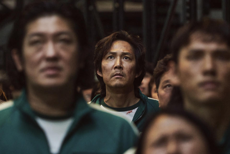 This image released by Netflix shows Lee Jung-jae, background center, in a scene from the popular Korean series "Squid Game." Jung-jae was nominated for an Emmy Award for best lead actor in a drama series. (Netflix via AP)