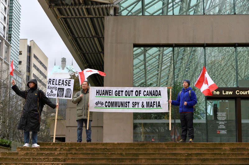 Protesters hold signs outside of B.C. Supreme Court during Huawei Chief Financial Officer Meng Wanzhou's extradition hearing in Vancouver