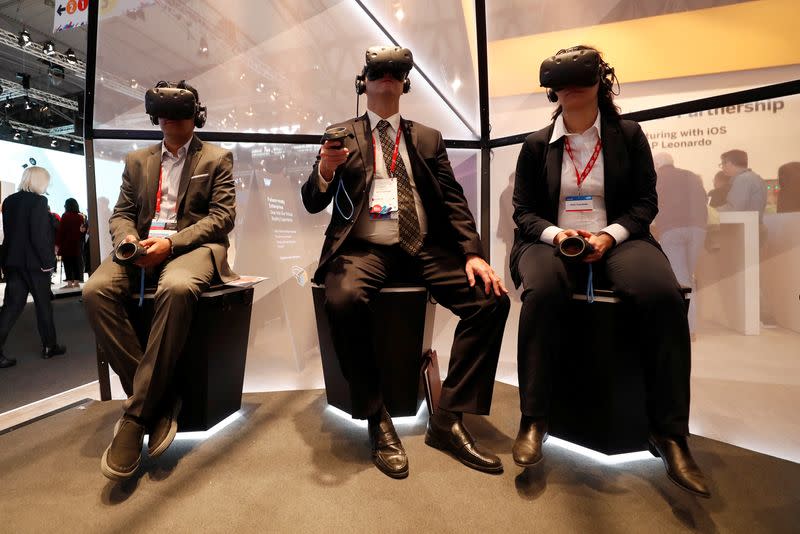 FILE PHOTO: Visitors check out VR headsets at the Mobile World Congress in Barcelona