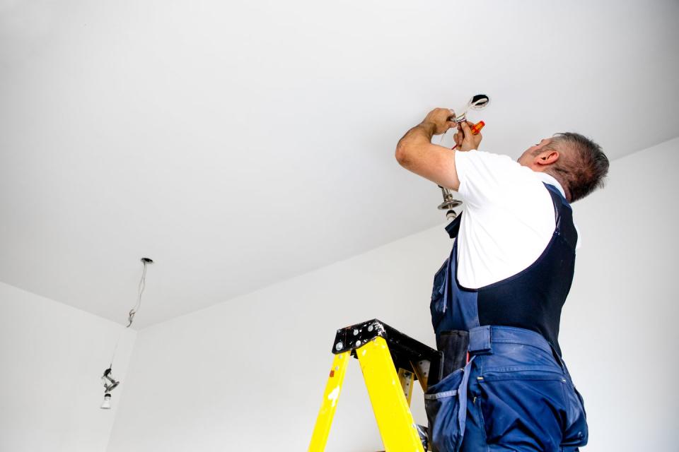 a repairman a male electrician is fixing the light installing led light into ceiling fixture