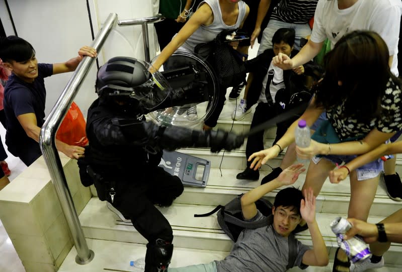 A riot police officer scuffles with protesters as he tries to detain a protester at a shopping mall in Tai Po in Hong Kong