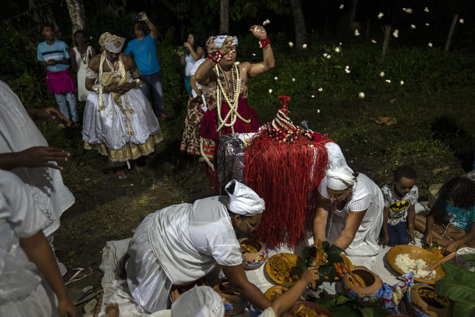 Thiago Viana, also known as Father Thiago of Oxum, tosses out pop corn during a ritual honoring Obaluae, the deity of earth and health, at the Afro Brazilian faith Candomble temple, on the outskirts of Salvador, Brazil, Sunday, Sept. 18, 2022. Viana was caught in the crossfire of a religiously tinged political attack on former President Luiz Inacio Lula da Silva, who leads all polls against incumbent Jair Bolsonaro, in the Oct. 2 presidential election. (AP Photo/Rodrigo Abd)