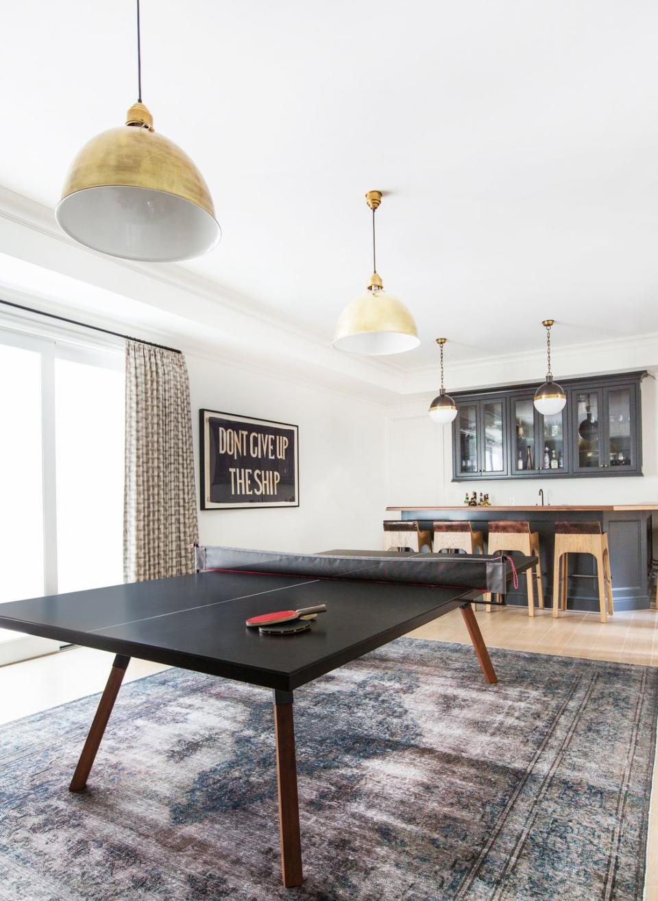 <p>Make it adult-friendly and party-proof by putting a bar in back. To give it a more formal, finished feel, hang stylish pendant lights an put your foosball table, ping pong table, pinball machine, pool table, or whatever your game of choice is over a colorful area rug. </p>