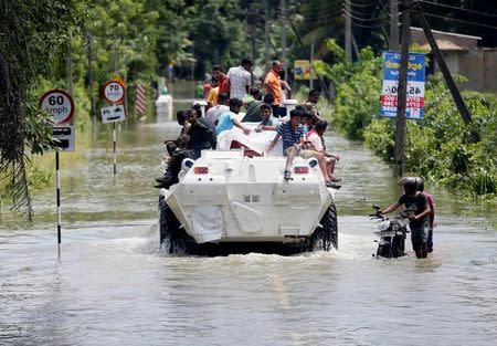 People are transported on top of an armoured personnel carrier on a flooded road as a man pushes his bike thorugh the water, in Bulathsinhala village, in Kalutara, Sri Lanka May 27, 2017. REUTERS/Dinuka Liyanawatte