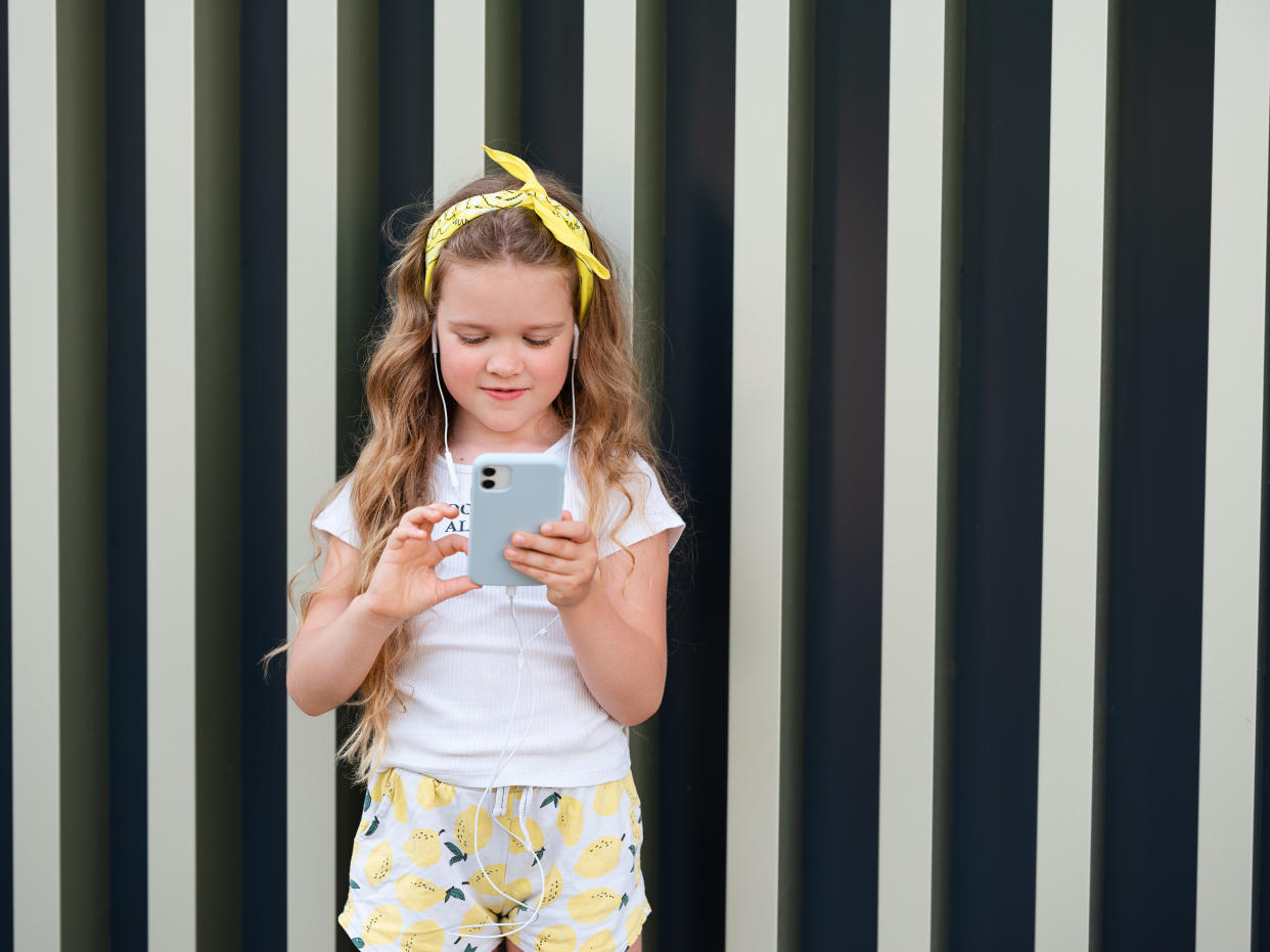 A young girl gazes at her smartphone.