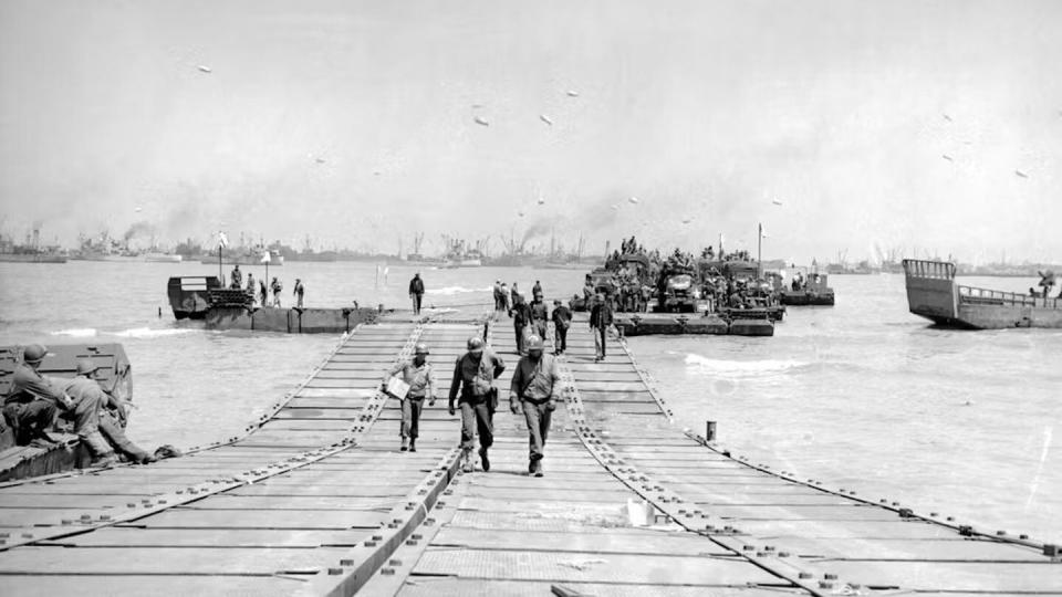 U.S. troops walk across a double-wide floating causeway at Omaha Beach in 1944. (Source: Seabee Museum. Seabee Museum)