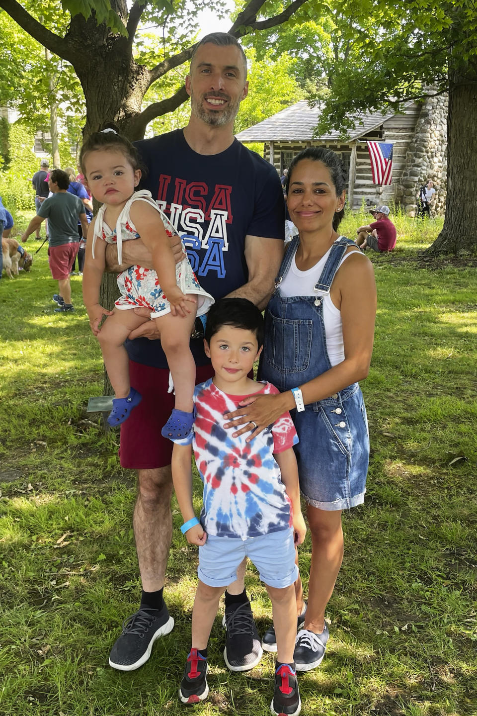 Kevin Flynn and Jessica Morales with their children pose for a photo during Independence Day Community Picnic in Highland Park, Ill., Tuesday, July 4, 2023. One year after a shooter took seven lives at the city's annual parade, community members are planning to honor the victims and reclaim the space to move forward. (AP Photo/Claire Savage)