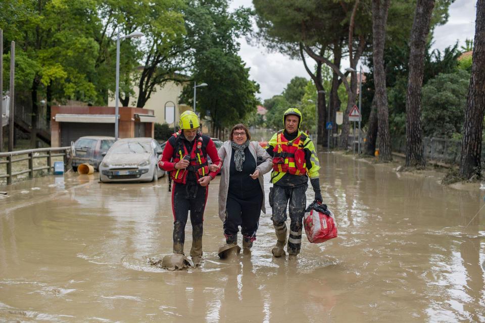 Firefighters help a woman reach safety in Faenza. (Reuters)