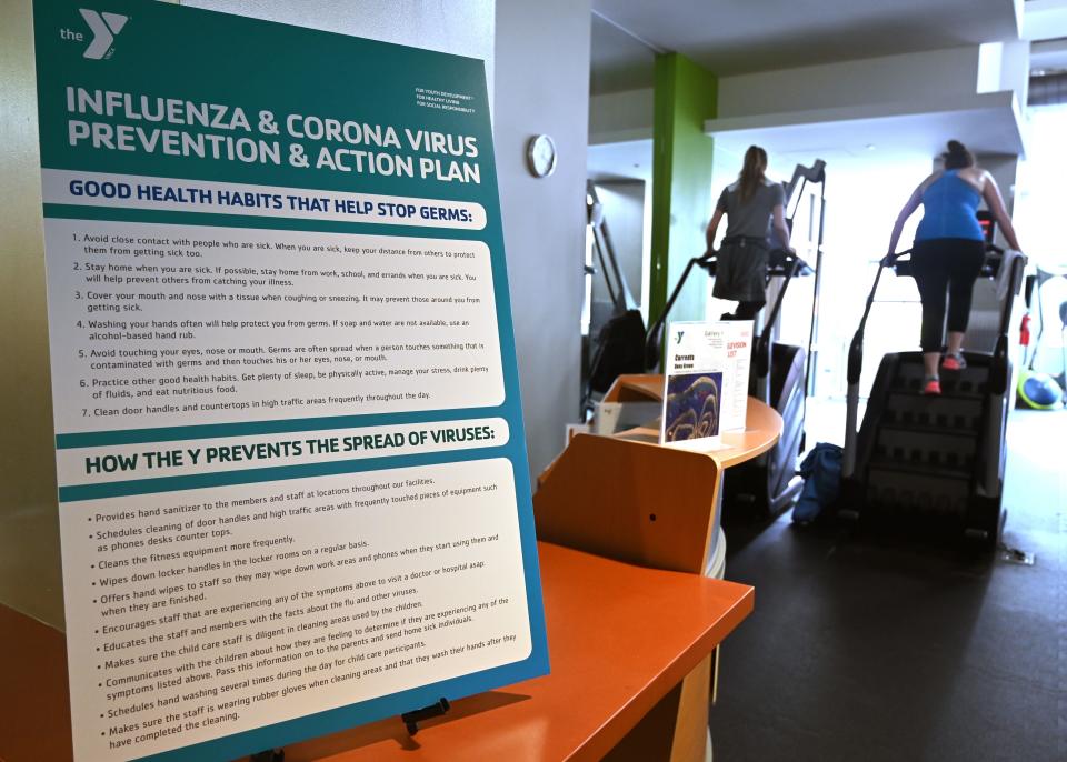 A poster informs guests about health habits and an action plan to fight the coronavirus as people exercise at a YMCA community center and gym in Washington, DC on March 12, 2020. - The COVID-19 virus has so far infected more than 130,000 people globally and killed over 4,900, according to an AFP tally with over 1,300 people infected and killed 38 in the United States. (Photo by EVA HAMBACH / AFP) (Photo by EVA HAMBACH/AFP via Getty Images)