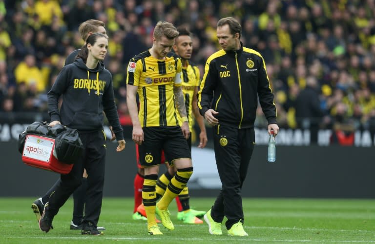 Dortmund's forward Marco Reus (C) goes off injured during the German First division Bundesliga football match between Borussia Dortmund and Bayer 04 Leverkusen in Dortmund, western Germany, on March 4, 2017