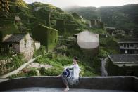 A tourist poses for photos in the abandoned fishing village of Houtouwan on the island of Shengshan July 25, 2015. (REUTERS/Damir Sagolj)