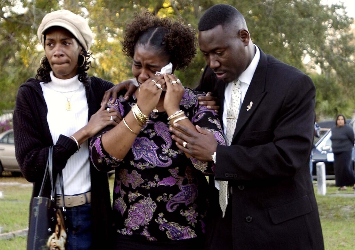 FILE - In this Tuesday, March 14, 2006 file photo, Gina Jones, center, mother of 14-year-old Martin Lee Anderson, is comforted by her sister, Debbie Williams, and attorney Benjamin Crump, after reburying her son in Panama City, Fla. Jones said Tuesday she wants justice now that a second autopsy showed that he did not die from a blood disorder as a medical examiner initially ruled. (AP Photo/Mari Darr-Welch)