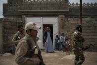 In this April 5, 2019 photo, residents watch as local militia and Iraqi army soldiers walk past their home during a raid in Badoush, Iraq. (AP Photo/Felipe Dana)