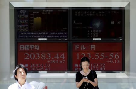 People stand in front of electronic boards showing Japan's Nikkei average (L) and the exchange rates between the Japanese yen against the U.S. dollar outside a brokerage in Tokyo July 14, 2015. REUTERS/Toru Hanai