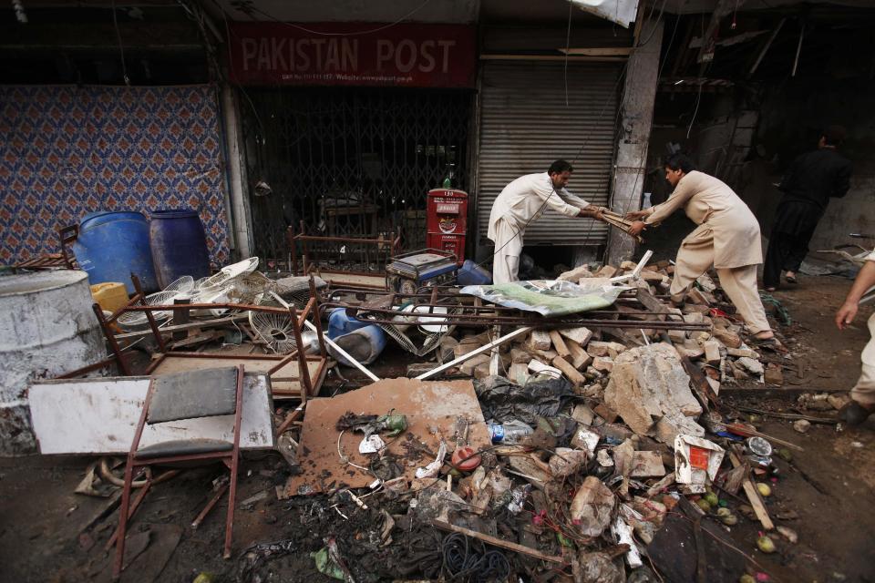 Men collect their belongings from the debris of a damaged building after it was hit by a bomb blast, which happened on Sunday, in Peshawar