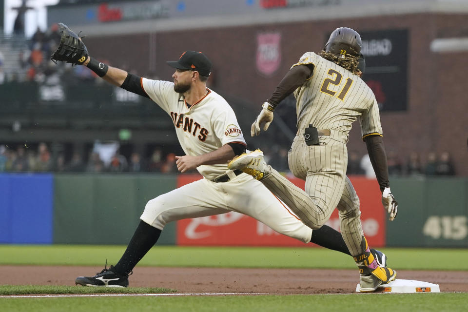 San Diego Padres' Fernando Tatis Jr., right, beats the throws to first base on his base hit next to San Francisco Giants first baseman Brandon Belt during the first inning of a baseball game in San Francisco, Wednesday, Sept. 15, 2021. Tatis Jr. and other players are wearing number 21 in honor of Roberto Clemente Day. (AP Photo/Jeff Chiu)