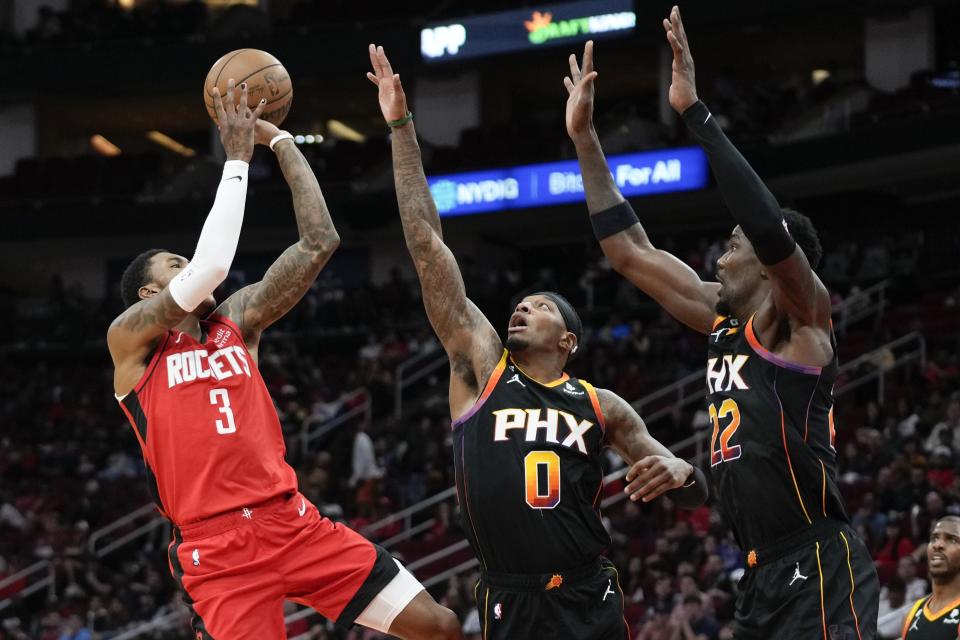 Houston Rockets guard Kevin Porter Jr. (3) shoots as Phoenix Suns forward Torrey Craig (0) and center Deandre Ayton defend during the first half of an NBA basketball game, Tuesday, Dec. 13, 2022, in Houston. (AP Photo/Eric Christian Smith)