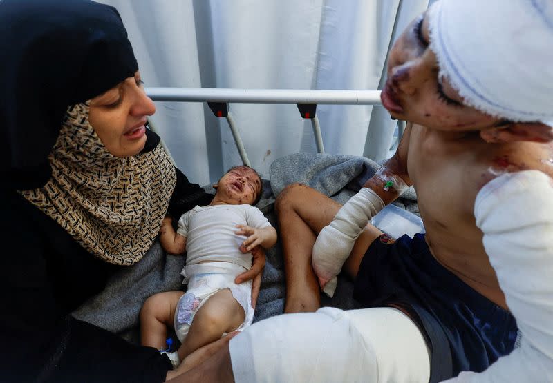 Palestinian child Tareq Qamar, who was injured in an Israeli strike that killed his mother, is carried by his aunt as his brother Mohammed who was wounded along with him reacts on a bed, at Nasser hospital, in Khan Younis in the southern Gaza Strip