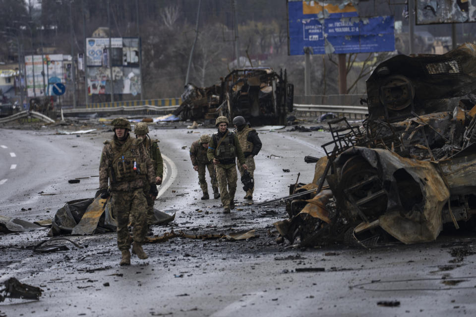 Ukrainian soldiers walk next to destroyed Russians armored vehicles in Boucha, Ukraine, Saturday, April 2, 2022. (AP Photo/Rodrigo Abd)