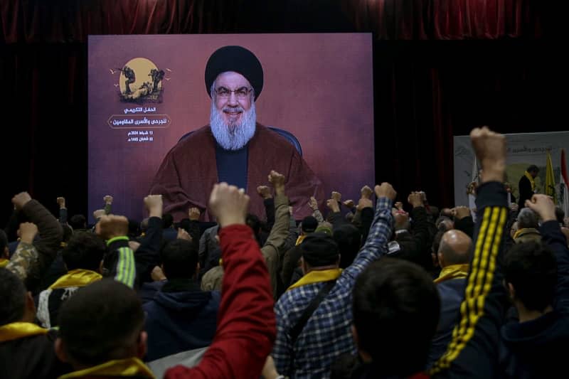 Supporters of the Iranian-backed Hezbollah group raise their fists and cheer, as they listen to a speech by Hassan Nasrallah, Secretary-general of Hezbollah, who appears via a video link, during an event to mark the "Wounded Resistance Fighter Day". Marwan Naamani/dpa