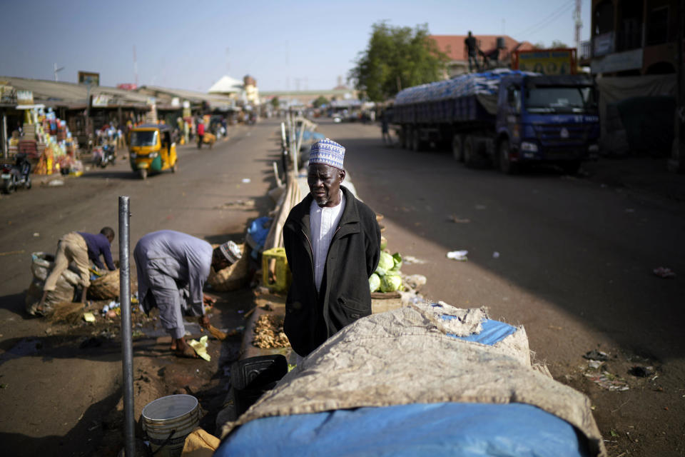 A Nigerian salesman stands in the middle of the normally busy street outside the central market in Kaduna, Nigeria, Saturday Feb. 16, 2019. Nigeria's electoral commission delayed the presidential election until Feb. 23, making the announcement a mere five hours before polls were set to open Saturday. (AP Photo/Jerome Delay)