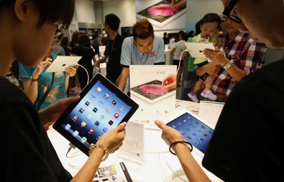 FILE- In this Friday, April 20, 2012, file photo, vsitors look at new iPad tablet computers at an Apple store in Klang, outside Kuala Lumpur, Malaysia, Friday, April 20, 2012. Apple is set to report another record quarterly profit on Tuesday, April 24, 2012, continuing the relentless string of results that’s made it the world’s most valuable company. (AP Photo/Lai Seng Sin)