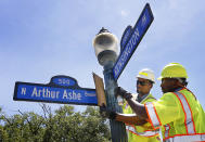 Richmond employees Andre Cannady, left, and Silas Poindexter install an Arthur Ashe Boulevard sign at the intersection with Kensington Avenue in Richmond, Va., Saturday, June 22, 2019. Groundbreaking black tennis player Arthur Ashe Jr.'s hometown of Richmond has renamed a major thoroughfare after him, after years of effort. (Alexa Welch Edlund/Richmond Times-Dispatch via AP)