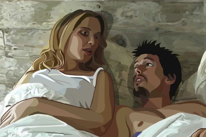 Julie Delpy and Ethan Hawke laying in bed and looking at each other in Waking Life.