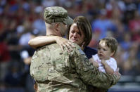 <p>Mandy Wilkes, center, cries as she is surprised by her husband, U.S. Air Force Reserve Staff Sgt. Mark Wilkes on leave from serving in Afghanistan, while holding their son Jett, right, during a ceremony honoring military families in the fourth inning of a baseball game between the Atlanta Braves and the Cincinnati Reds, Saturday, April 26, 2014, in Atlanta. (AP Photo/David Goldman) </p>