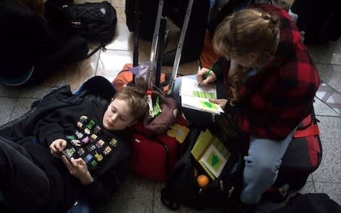 Heidi Harrington, right, and her son Dillon wait to check in for their flight to New York in a dark terminal at Hartsfield-Jackson International Airport - Credit: Steve Schaefer/AP