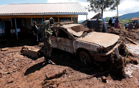 A military officer assesses a damaged car after a dam burst, which unleashed water at nearby homes, in Solio town near Nakuru, Kenya May 10, 2018. REUTERS/Thomas Mukoya