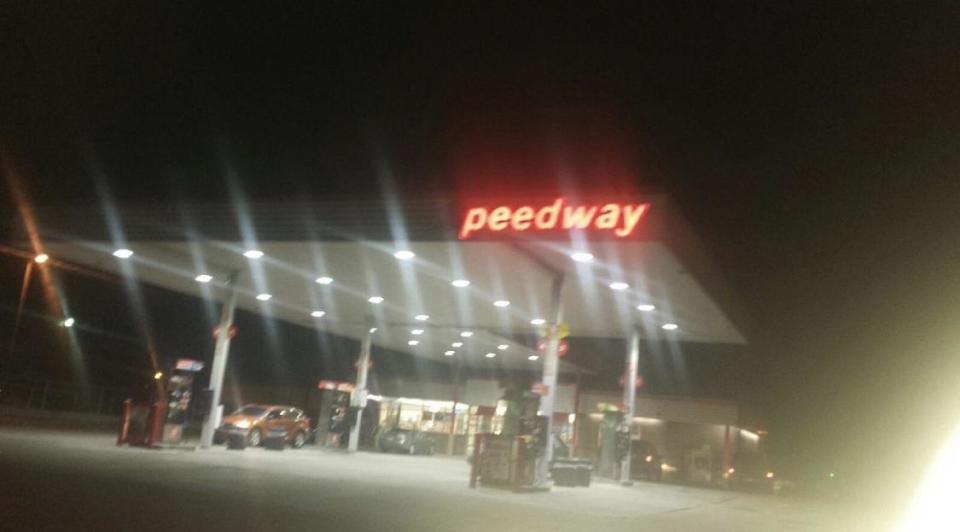 A poorly lit photo of a gas station at night with a partially burnt out sign that attempts to read 