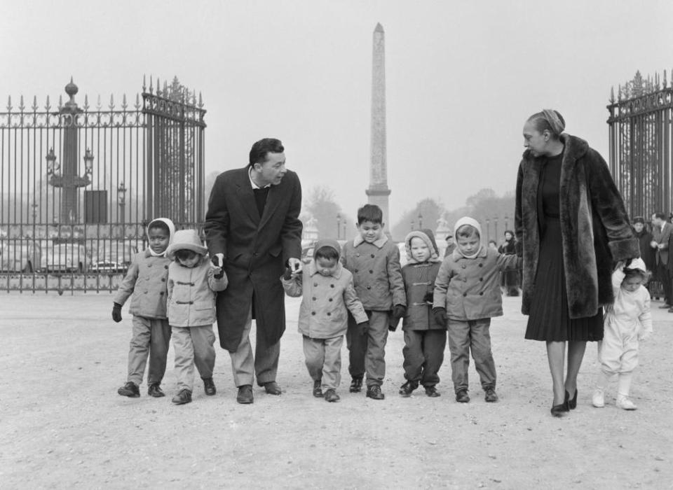 Josephine Baker and her husband, Jo Bouillon, stroll through the Tuileries in Paris with seven of the children they adopted.