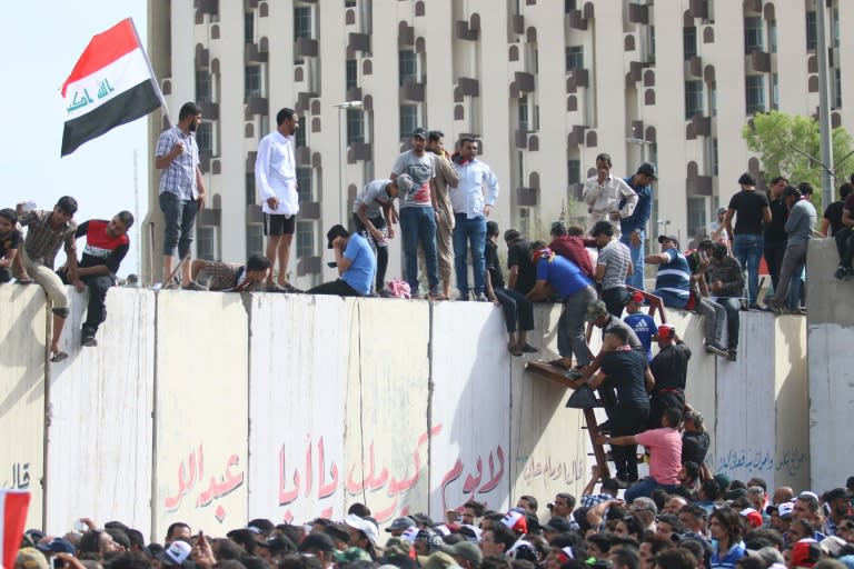 Iraqi protesters climb over a concrete wall surrounding the parliament after breaking into Baghdad's heavily fortified "Green Zone" on April 30, 2016